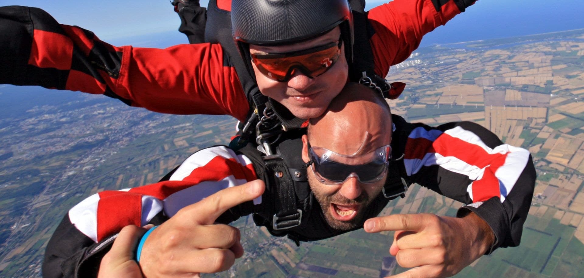 The handcam's own view: the passenger's face right by the lens, the instructor above, fields far below