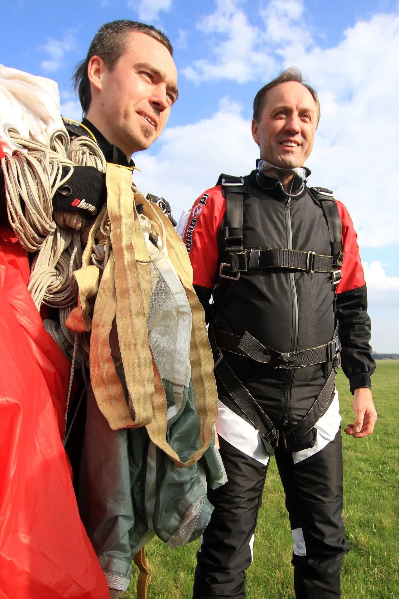 Two jumpers with a canopy over their shoulders moments after landing