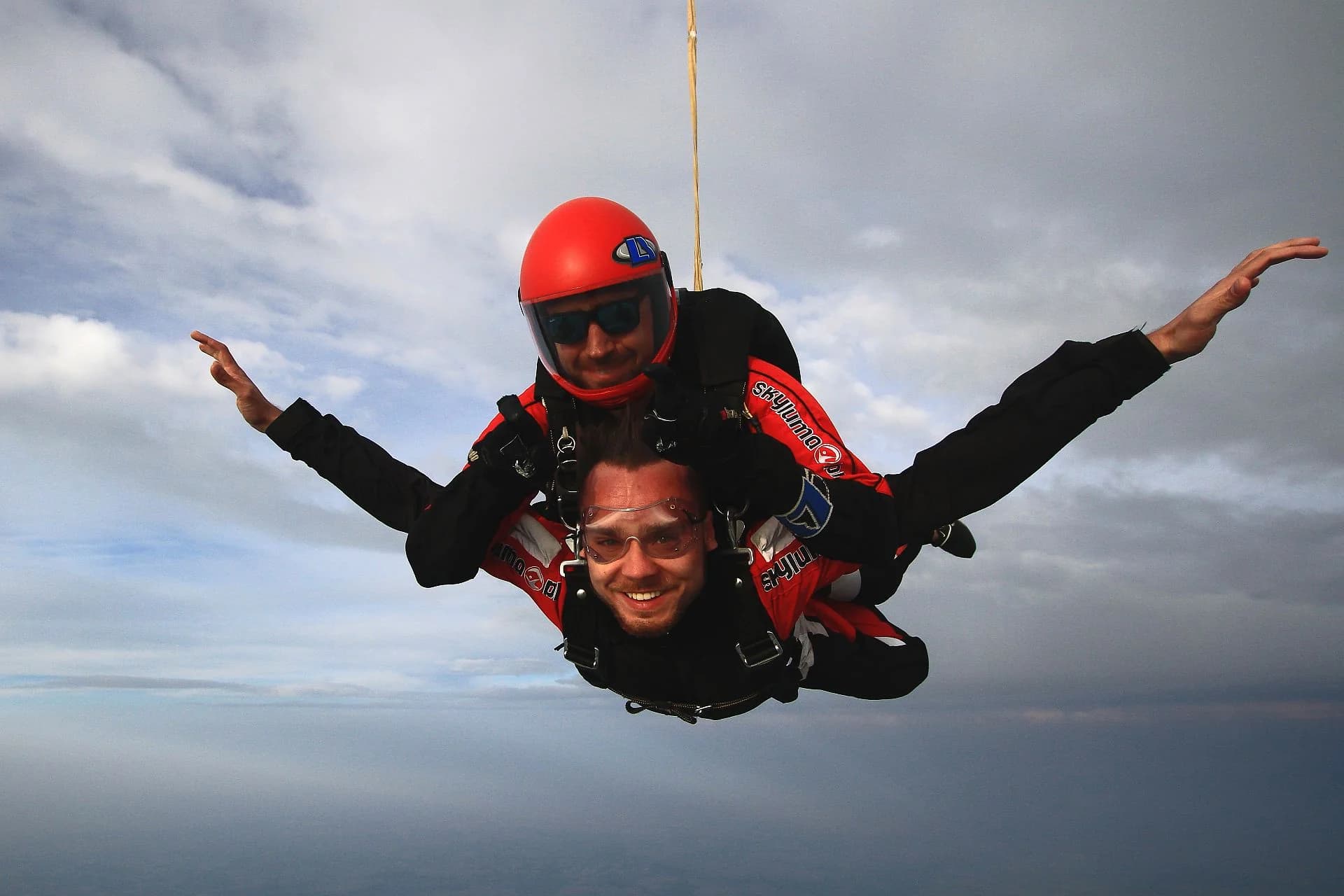 A huge grin in freefall, both arms spread wide