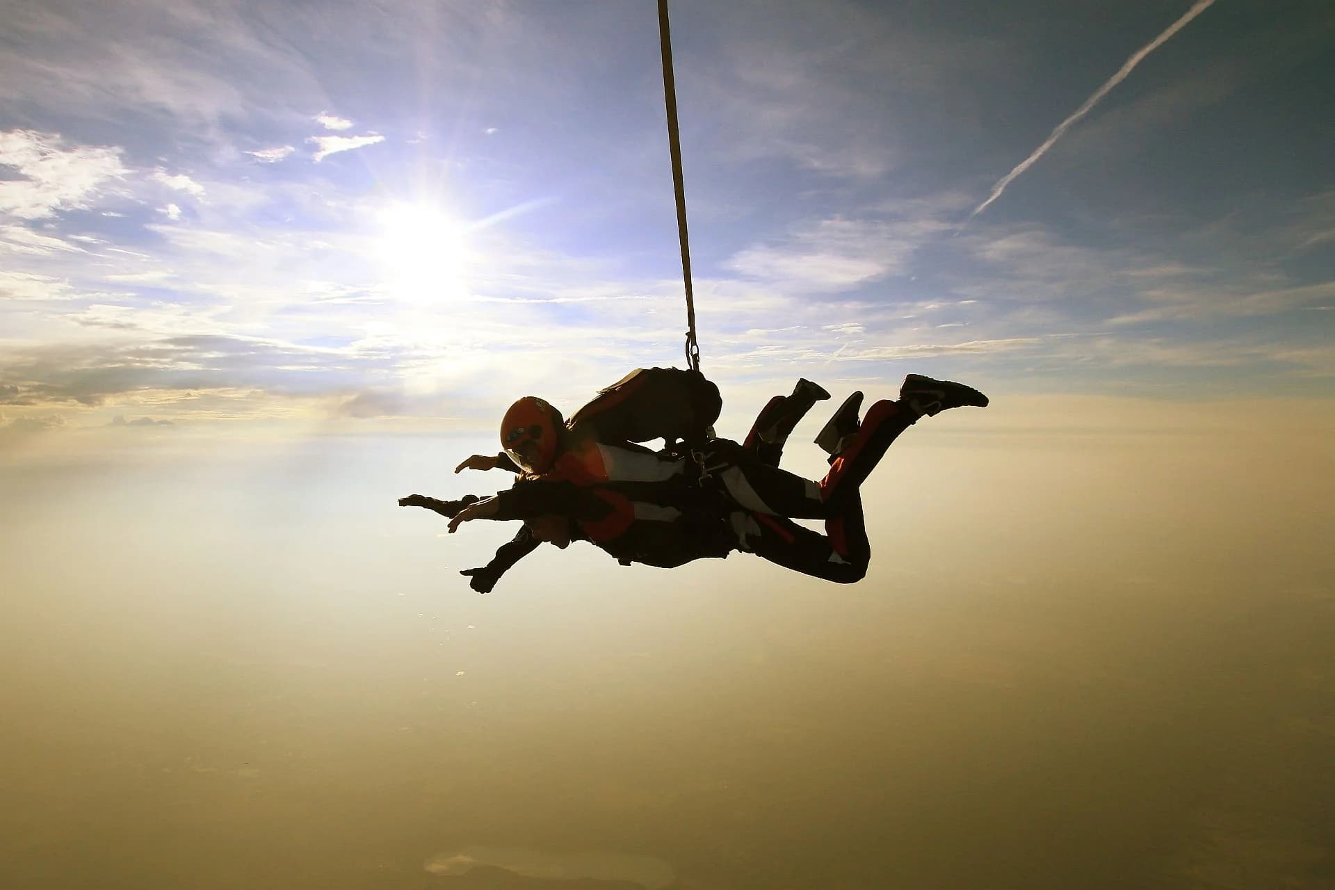 The tandem falls into golden evening light, above a sea of haze