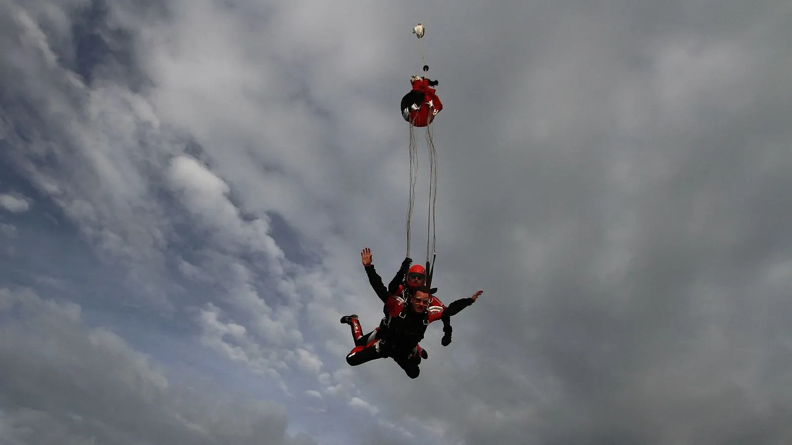 A tandem at the opening, the canopy leaving its bag against a stormy sky